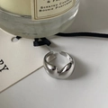 Detalle macro del anillo de corazón de metal líquido pulido con velas y cintas - Estilo abierto ajustable / Plateado