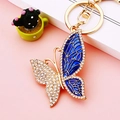 Golden butterfly keychain with blue enamel wing and clear rhinestones on pink backdrop - Blue Pattern Butterfly