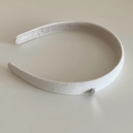 Close-up of white knitted headband with a silver heart charm on a minimalist background - Beige Apricot