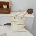 Dettaglio della tracolla di una borsa tote in tela con ricamo floreale arancione - Beige