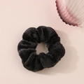 Dettaglio di un elastico in peluche nero su superficie rosa con una conchiglia di vetro - Nero