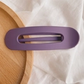 Detail of purple matte oval hair clip with hollow design on a textured background - Matte Purple