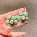 Detail of green floral enamel earring with white pearl center and gold-tone finish - Green