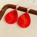 Dettaglio degli orecchini in resina rossa con metallo martellato su un panno di lino - Patchwork Oro-Rosso (Perno in Argento)