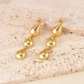 Close-up of triple-tiered golden teardrop tassel earrings on a textured stone surface - 3-Tier Teardrop / Gold