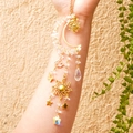 Detail of hanging suncatcher featuring gold crescent moon, crystals, and delicate metal charms - White Crystal