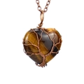 Detailed macro view of heart-shaped tiger eye stone with wire-wrapped tree of life design - Antique Copper + Tiger's Eye