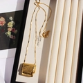 Elegant gold woven bag pendant necklace on jewelry box display with light shadow - Woven Bag Style / Gold