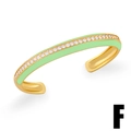 Dettaglio ravvicinato di smalto verde menta e zirconi su un bracciale rigido dorato - Verde