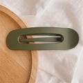 Macro view of olive green matte hair clip with rectangular cutout on wooden tray - Matte Fruit Green