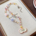 Close-up of a colorful beaded necklace with ceramic flower and bow charms on a linen tray - 17# Seed Bead Flower Waterdrop Bow Necklace