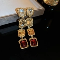 Macro shot of gold-plated geometric earrings with gradient champagne and red crystals - Earrings-Multicolor
