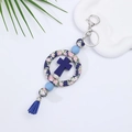 Blauer Silikon-Kreuz-Schlüsselanhänger mit floralem Ring und Quaste auf weißem Grund - Blaues Blumenmuster