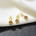 Macro shot of three golden rectangular charms with red floral zircon on a dark stone - Red Zirconia-Gold