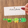 Main tenant une carte avec 6 paires de boucles d'oreilles en résine fruits et animaux - Thème Fruit Vert (E0998-1)