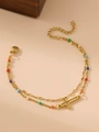 Macro detail of a 18K gold-plated double-layer bracelet with colorful beads and a cross - Hollow Cross Pendant / Gold