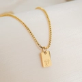 Close-up of a square 18K gold plated pendant necklace featuring the engraved letter F - Letter F