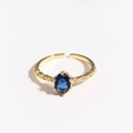 Close-up of golden adjustable ring with oval blue zircon and micro-pave accents - Dark Blue Gemstone Gold Plated