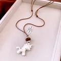 Detailaufnahme eines matten Einhorn-Anhängers mit brauner Perle an einer geflochtenen Kordel - Halskette-Silber-Kaffee