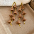 Detailed macro of golden beaded drop earrings with velvet flower petals in a cozy setting - Brown