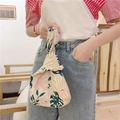 Close-up of tropical leaf print on linen wrist bag featuring a knot handle design - Pink Monstera