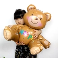 Large brown bear aluminum foil balloon with colorful HAPPY text for kids birthday party - HAPPY Assembly Bear