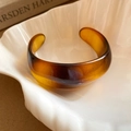 Detailopname van amberkleurige hars armband met vintage textuur op witte keramiek plaat - Koffie Brede Afgeronde Stijl (6#)