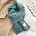 Detail of teal knitted scarf with ribbed edges and small emo label on white fabric - Haze Blue