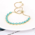 Detail view of gold chain bracelet featuring blue evil eye charms and adjustable slider - Lake Blue