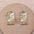 Macro shot of two vintage golden Tarot Moon pendants on a wooden pedestal with woven texture - Antique Gold THE MOON