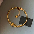 Makro-Detail von 18K vergoldetem Bambus-Armband mit graviertem Anhänger und Karabiner - Gold