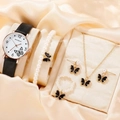 Close-up of black and gold butterfly watch set with pearl jewelry on silk fabric - Black