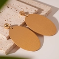 Dettaglio macro di grandi orecchini a cerchio ovali dorati con finitura satinata - Ovale / Oro