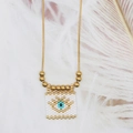 Detailed view of evil eye square pendant with blue beads and gold bead chain on feather - Cream White