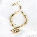 Close-up of gold beaded bracelet with zircon-encrusted letter A charm and adjustable cord - Letter R