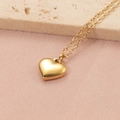 Dettaglio del ciondolo a cuore 3D dorato su catena sottile con sfondo in seta e pietra - Oro (12mm)