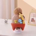 Close-up of pink and orange knitted baby hat with cartoon embroidery and pom-pom - Giraffe Light Khaki
