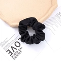 Dettaglio di un elastico per capelli in raso nero di alta qualità con finitura lucida e liscia - Nero