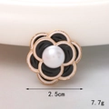 Detalle del accesorio de flor de camelia con perla grande y borde dorado fino - Camelia Negra