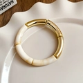 Detalle del contraste entre el metal dorado y la resina crema sobre el plato ondulado - 3# Brazalete-Dorado-Bambú