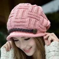 Close-up of pink knit hat featuring woven leather strap and vintage metal button detail - Pink