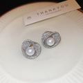 Primer plano de aretes de perlas plateadas con circonitas en bandeja de cerámica blanca - Plata (Pin de plata)