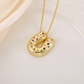 Detail shot of a puffy 18K gold letter U pendant with multi-colored zircons on silk - Letter U