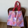 Tragetasche mit floralem Druck in Rosa-Violett und roten Griffen auf Holzstuhl - Rote Riemen Floral Kontrast