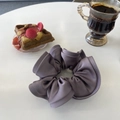Elegant mauve satin scrunchie with oversized folds on a white table with coffee - Temperament Purple