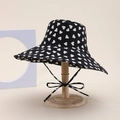 Black bucket hat with white heart pattern and adjustable chin strap on wooden stand - Heart Style / Black