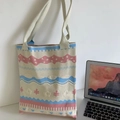 Detail of knitted tote bag with blue and pink patterns next to a laptop on desk - Floral Beige