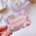 Handheld floral greeting card with Good Luck text and elegant pink blossoms - Rose Affair