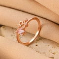 Rose gold bow-shaped ring with stars and zircon stones on a beige stone base - Rose Gold Star Zirconia Ring (WG-1057)