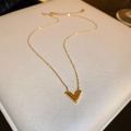 Detailed view of a gold V-shaped pendant necklace resting on a white leather jewelry box - Gold V-shape Necklace
